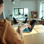 Un gestionnaire consultant des documents de copropriété sur un ordinateur portable dans un bureau moderne